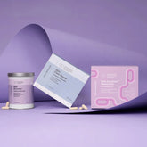 A skincare product set on a lavender studio background, featuring a white jar labeled Skin Reset, a light blue box labeled Skin Barrier, and a pink box labeled Skin Acne Mask, with a few beige capsules scattered in front.